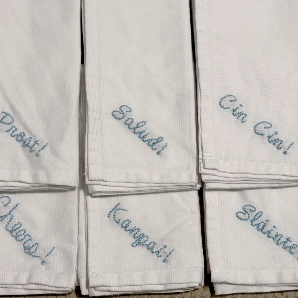 White Napkins with Blue Hand-Embroidered Cheers in Different Languages